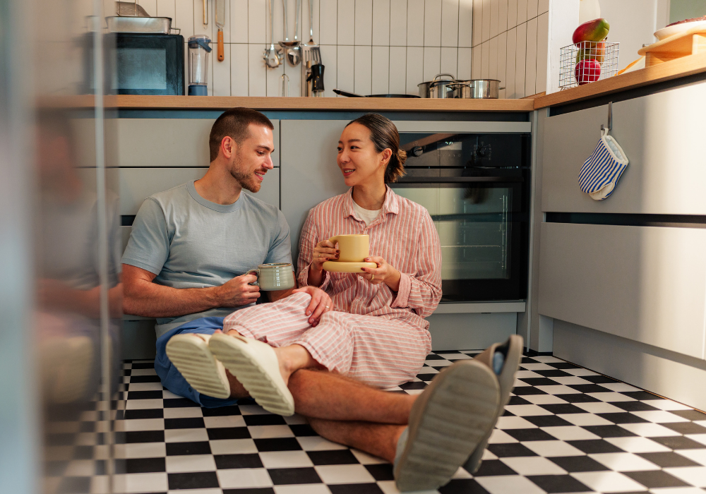 a man and woman sitting on the floor with cups of coffee
