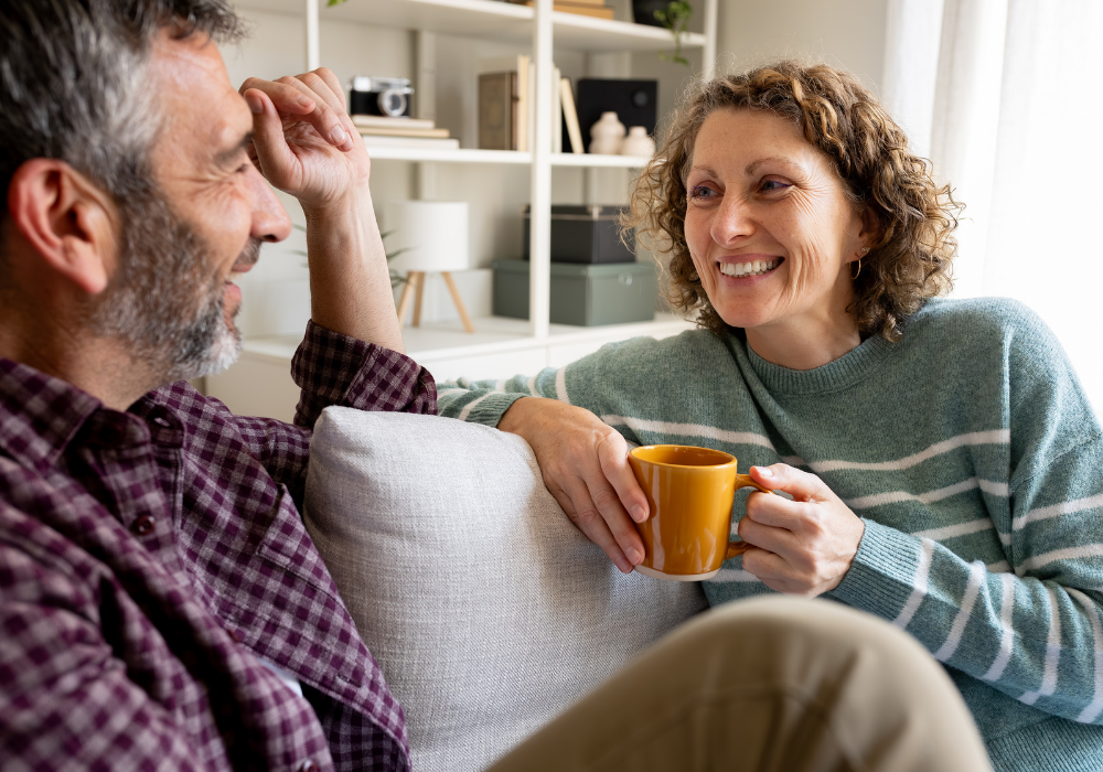a man and woman sitting on a couch and holding a cup