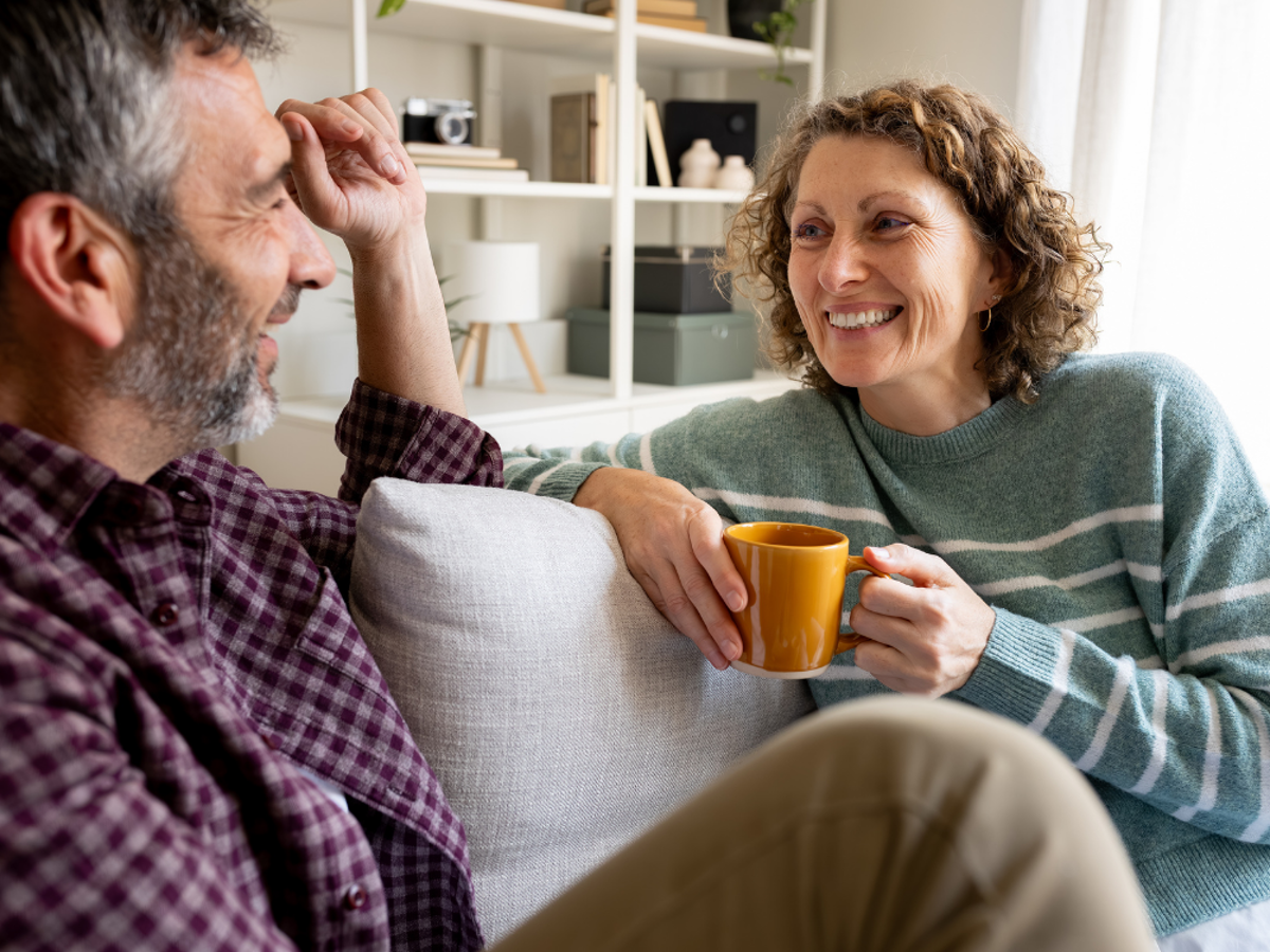 a man and woman sitting on a couch and holding a cup