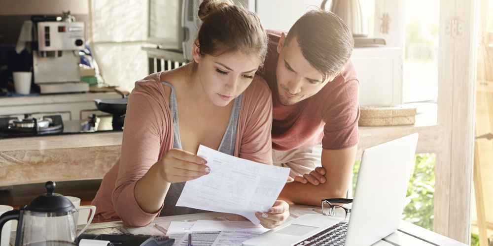Couple looking over paperwork together at their kitchen counter