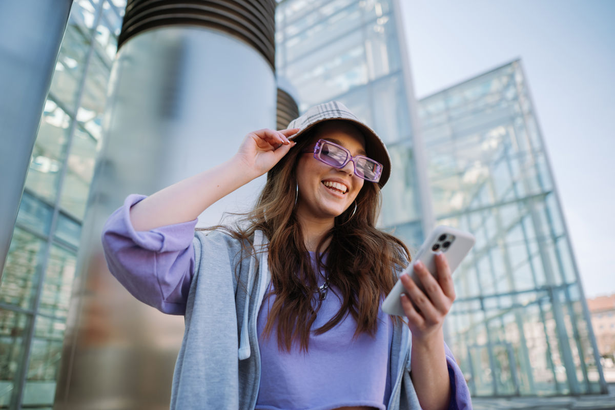 a woman wearing glasses and a hat looking at a phone