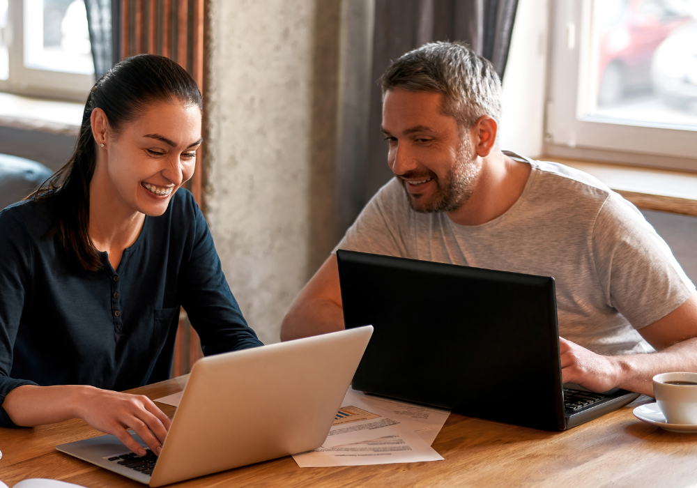 a man and woman sitting at a table with laptops