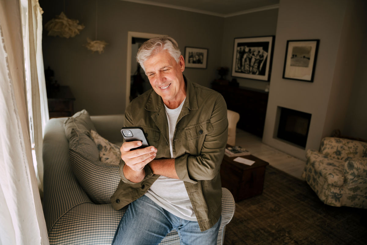 a man sitting on a couch looking at a cell phone