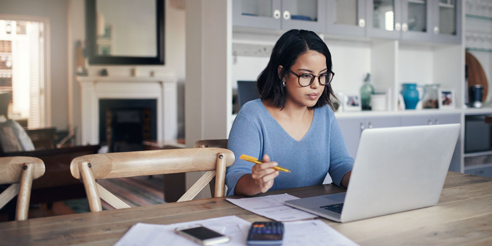 Woman planning financial goals for the new year using laptop and paperwork at home
