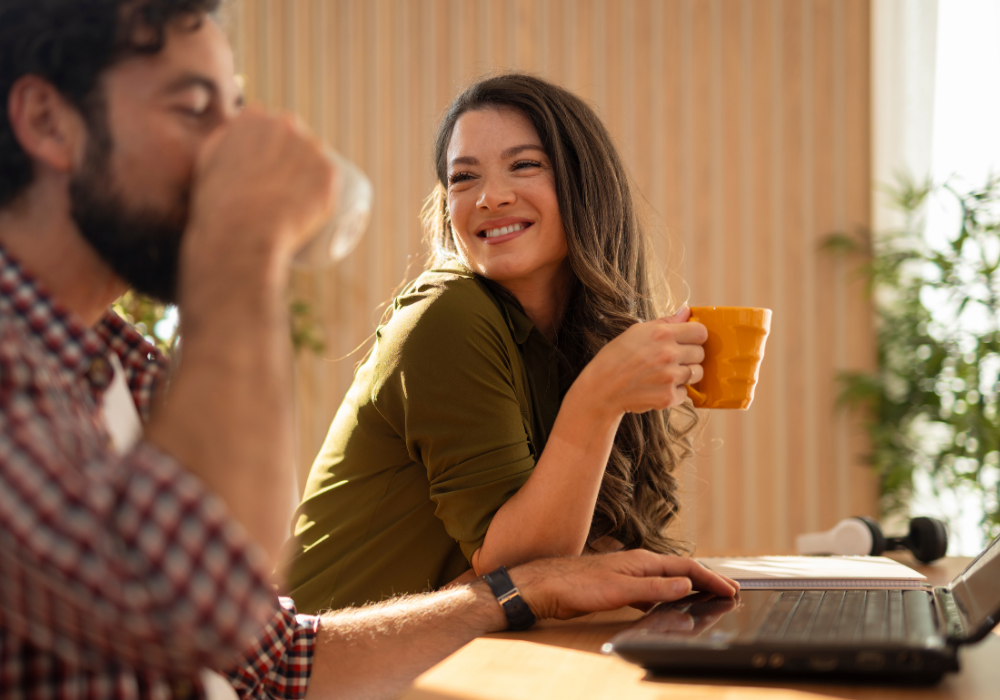a man and woman sitting at a table with a laptop